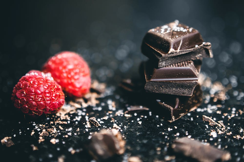 The Science Behind Chocolate’s Next Big Transformation Close-up of dark chocolate pieces and raspberries, perfect for gourmet dessert ideas.