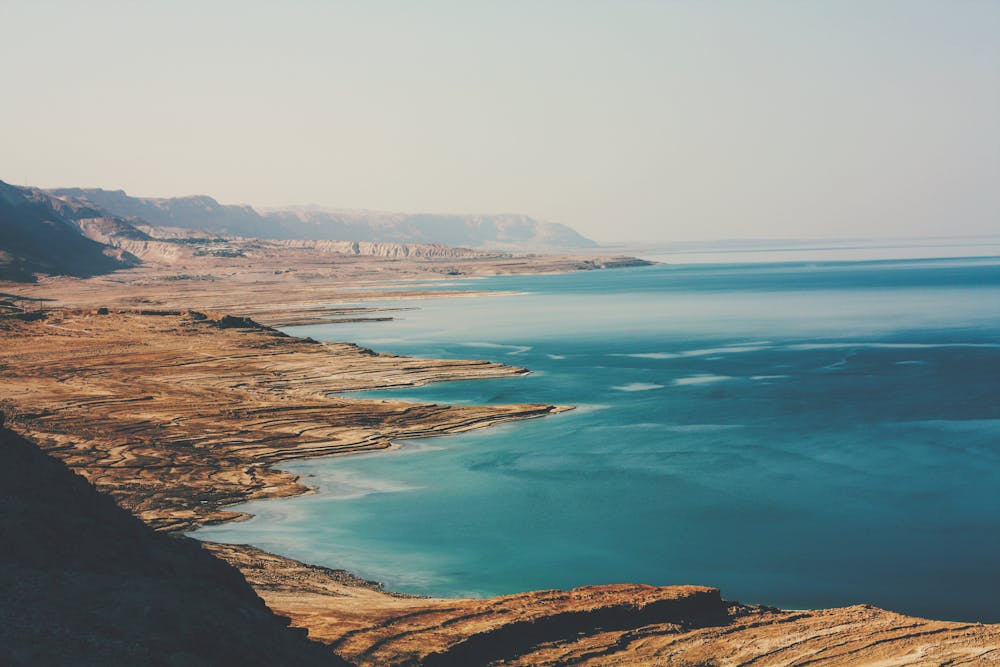 Snowing Salt in the Dead Sea is Nature’s Underground Architect A breathtaking aerial view of the Dead Sea's coastline, capturing its rugged beauty and serene blue waters.