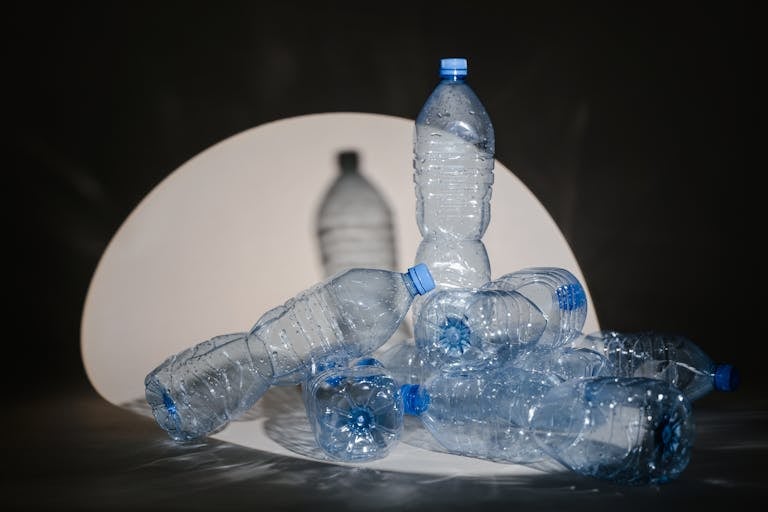 A group of used plastic bottles illuminated under a dramatic spotlight setting.