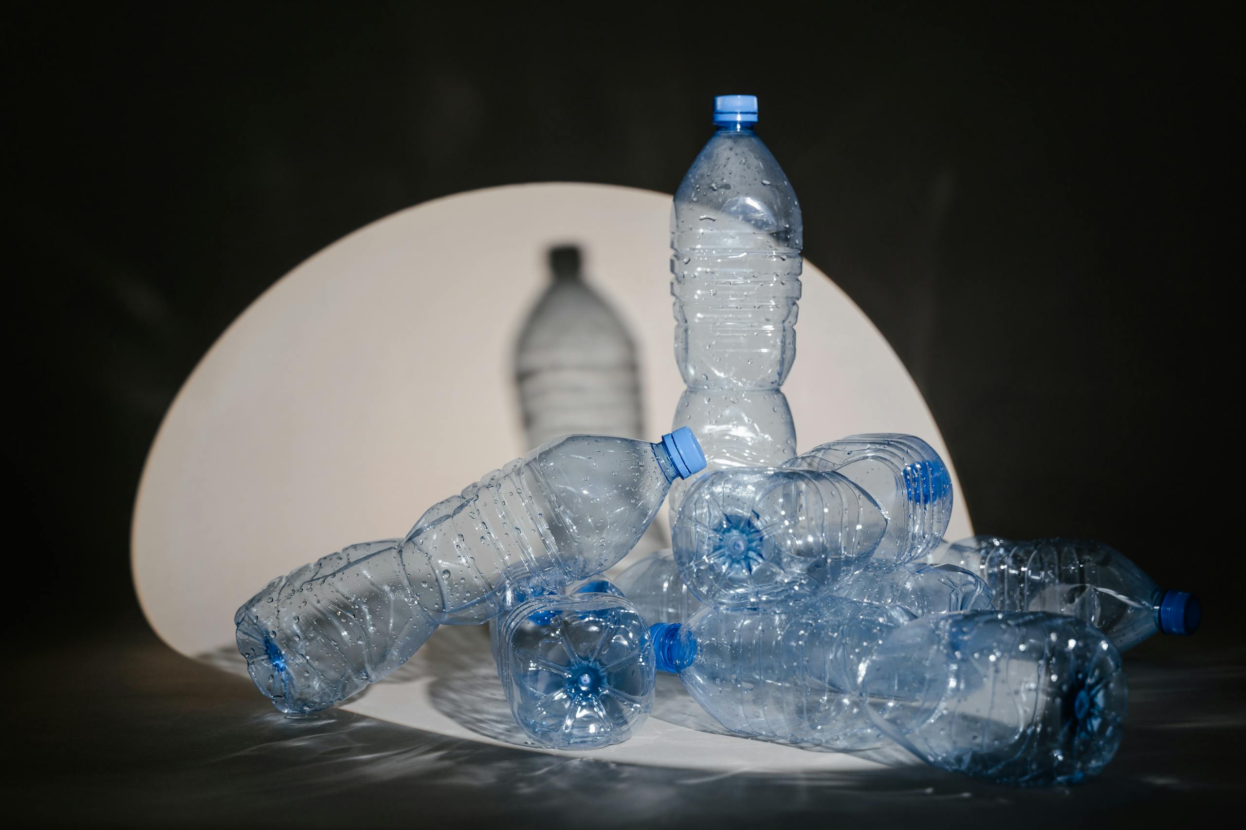 A group of used plastic bottles illuminated under a dramatic spotlight setting.