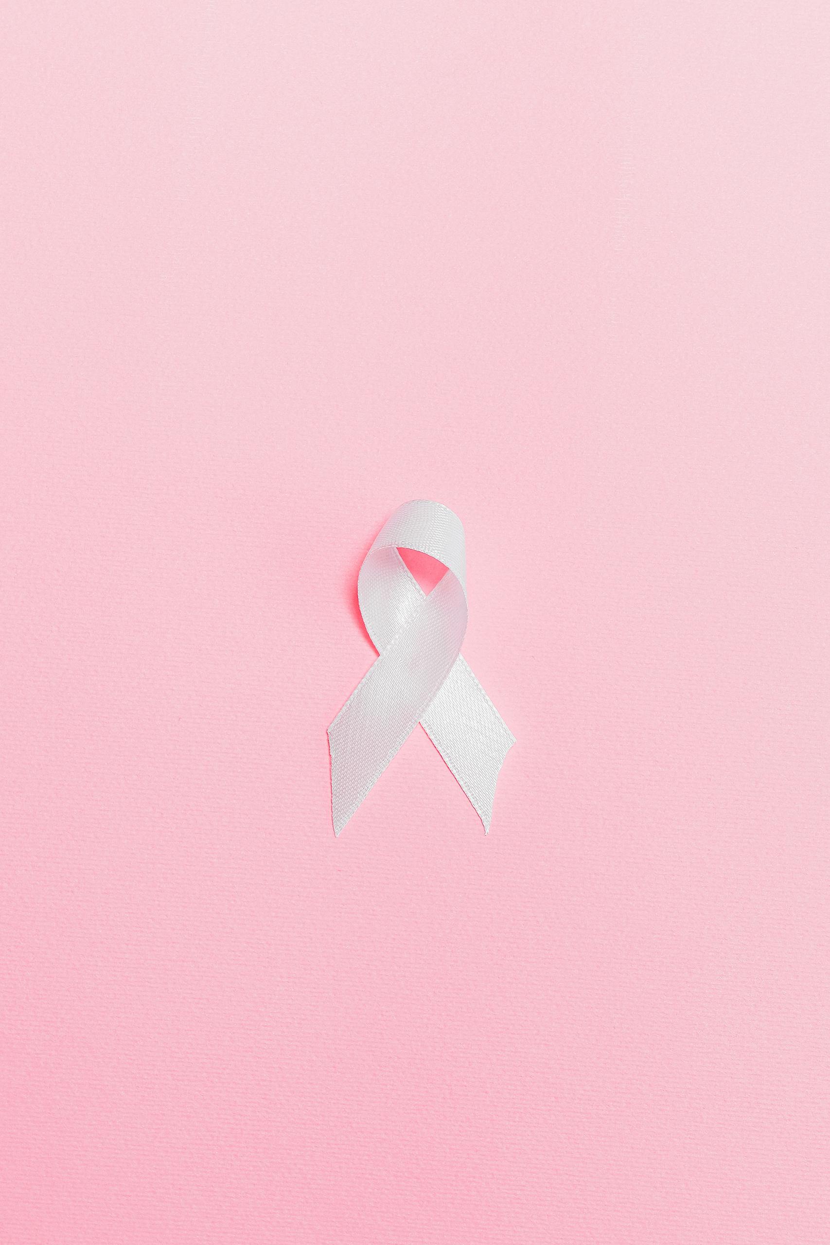 How Physical Pressure Reprograms Cancer Cells Into More Invasive States A pink ribbon symbolizing breast cancer awareness set against a light pink background.