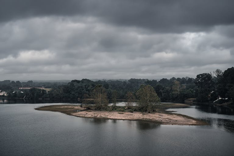A serene river scene with an island and moody overcast clouds, perfect for nature enthusiasts.