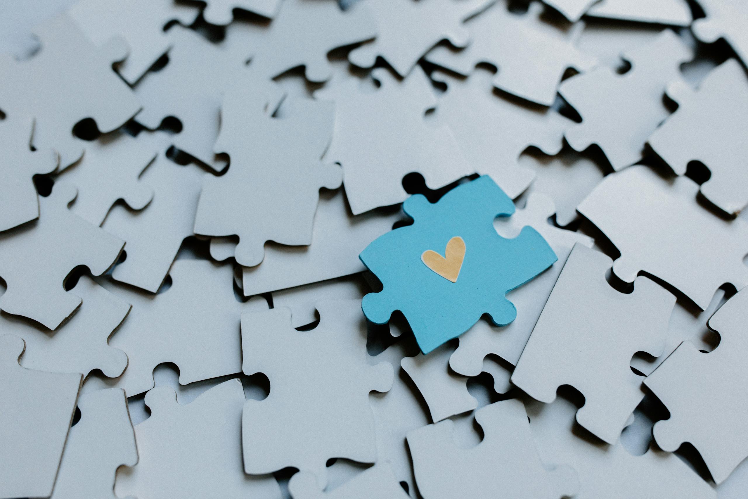 New Global Study Finds Alternative Autism Therapies Lack Strong Scientific Evidence A single blue puzzle piece with a heart amid scattered pieces, symbolizing connection.