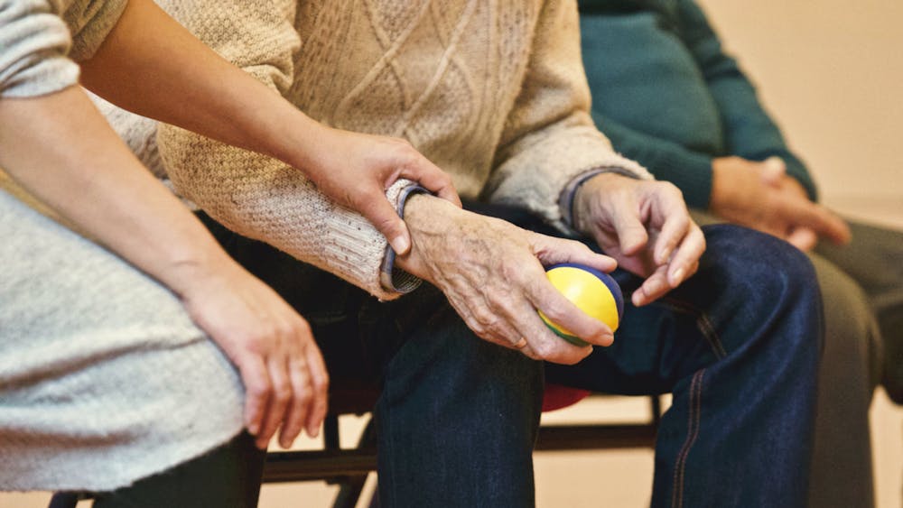 Could Your Nose Be the Earliest Clue to Alzheimer’s? An elderly person receives support from a caregiver, holding hands indoors, showcasing compassion.