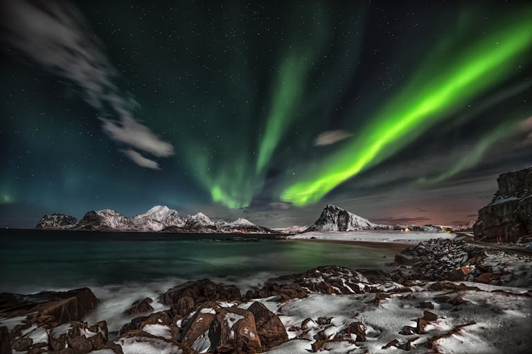 Captivating view of the Northern Lights over snow-covered Lofoten Islands at night.