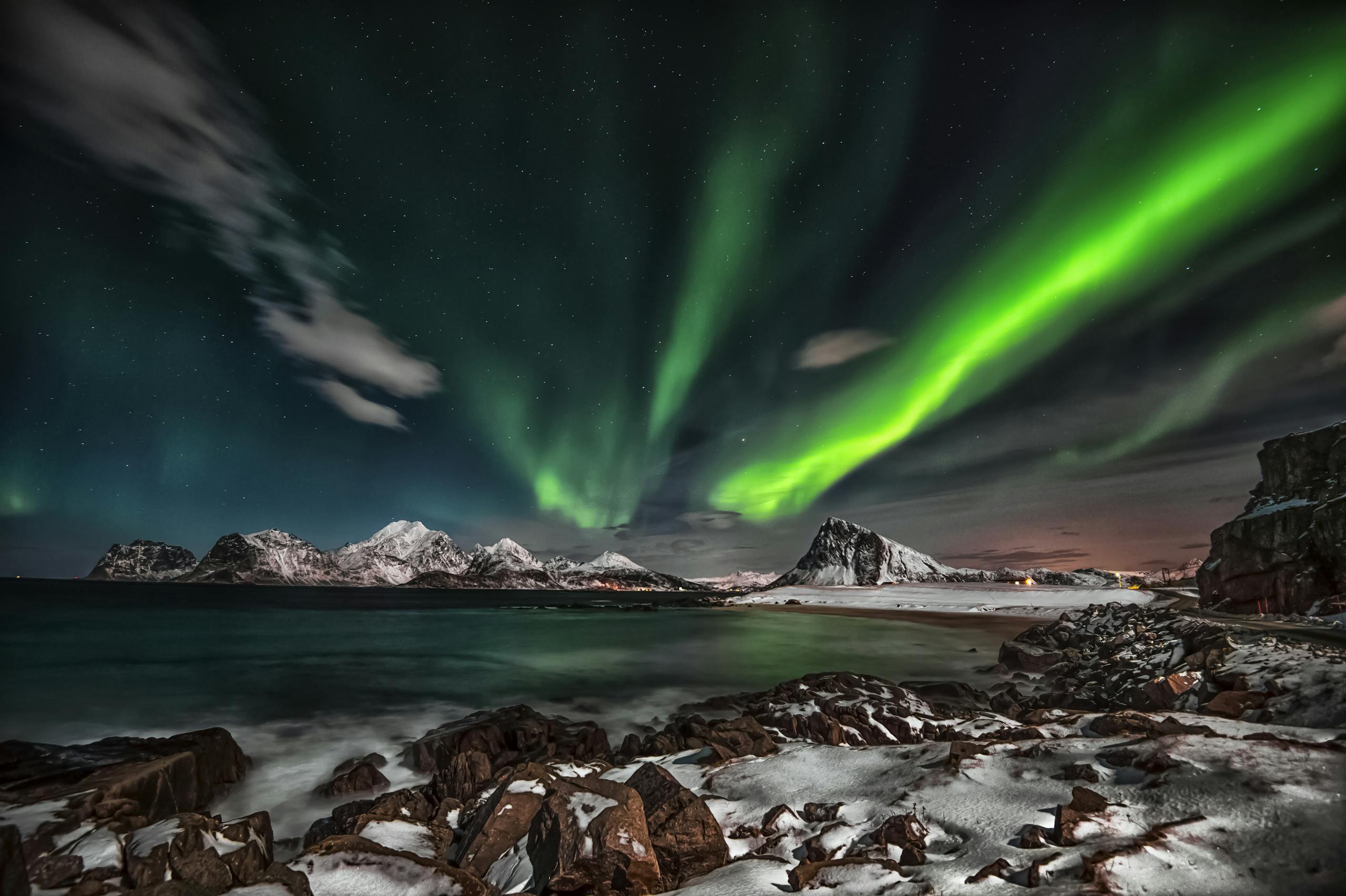 Captivating view of the Northern Lights over snow-covered Lofoten Islands at night.