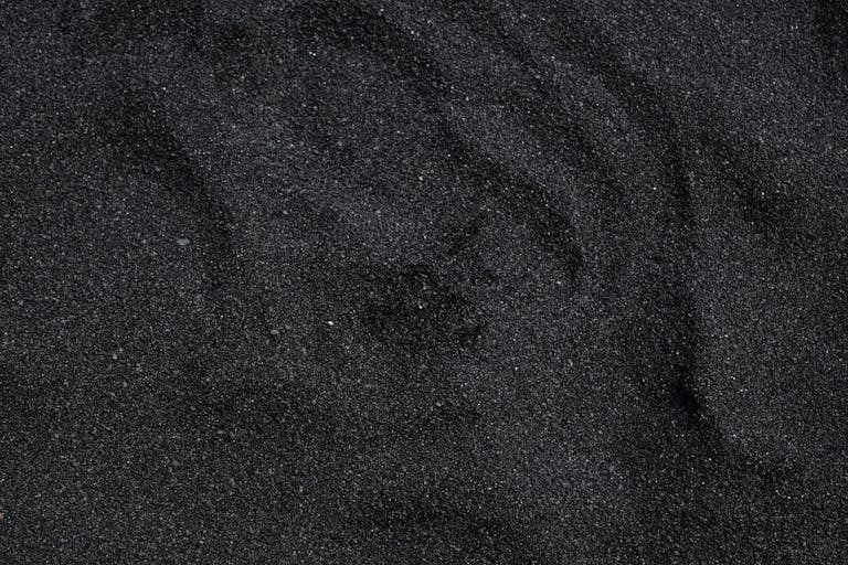 Close-up of black sand texture from Waimea Beach in Hawaii. Ideal for backgrounds.