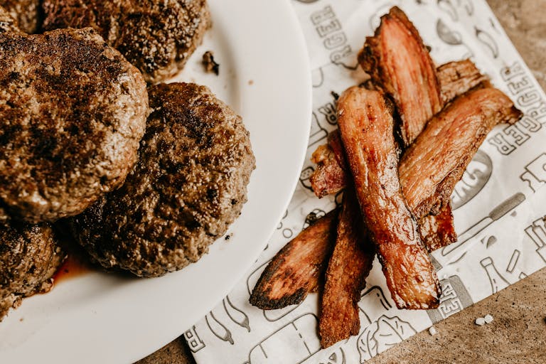Delicious grilled beef patties served with crispy bacon strips on a rustic setting.