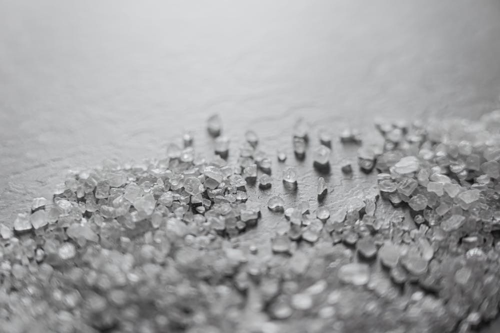 Very Few Americans Use Salt Substitutes Despite Clear Benefits for Blood Pressure Detailed macro shot of scattered rock salt crystals with soft focus, creating a textured abstract pattern.