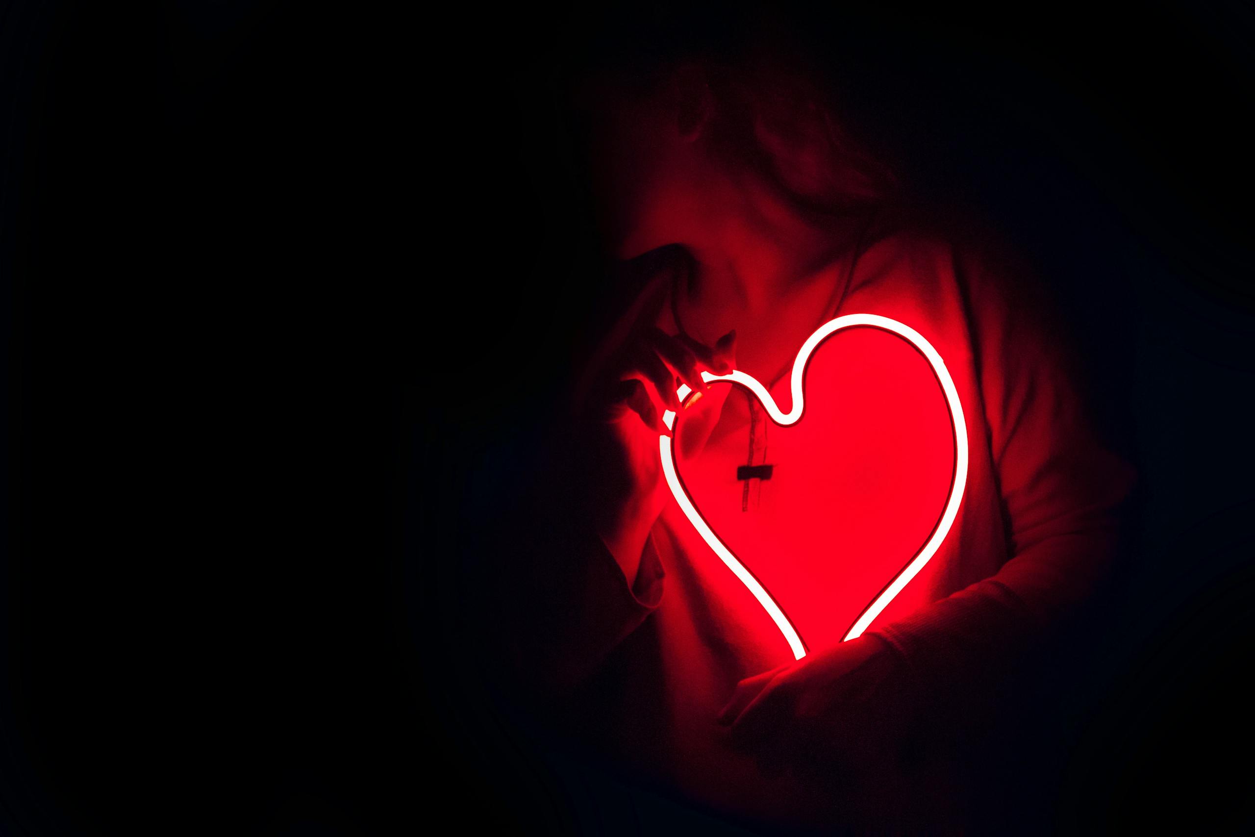 Heart Attacks May Be Linked to Hidden Infections: New Research Opens Surprising Possibilities Silhouette of a person with a glowing red neon heart in the dark, symbolizing love.