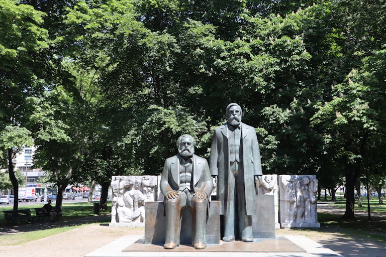 Statues of Karl Marx and Friedrich Engels in Berlin park, sunny day.