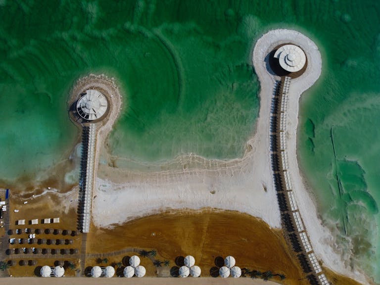 Stunning drone shot of the Dead Sea's salt formations and pavilions, showcasing unique water patterns in Israel.