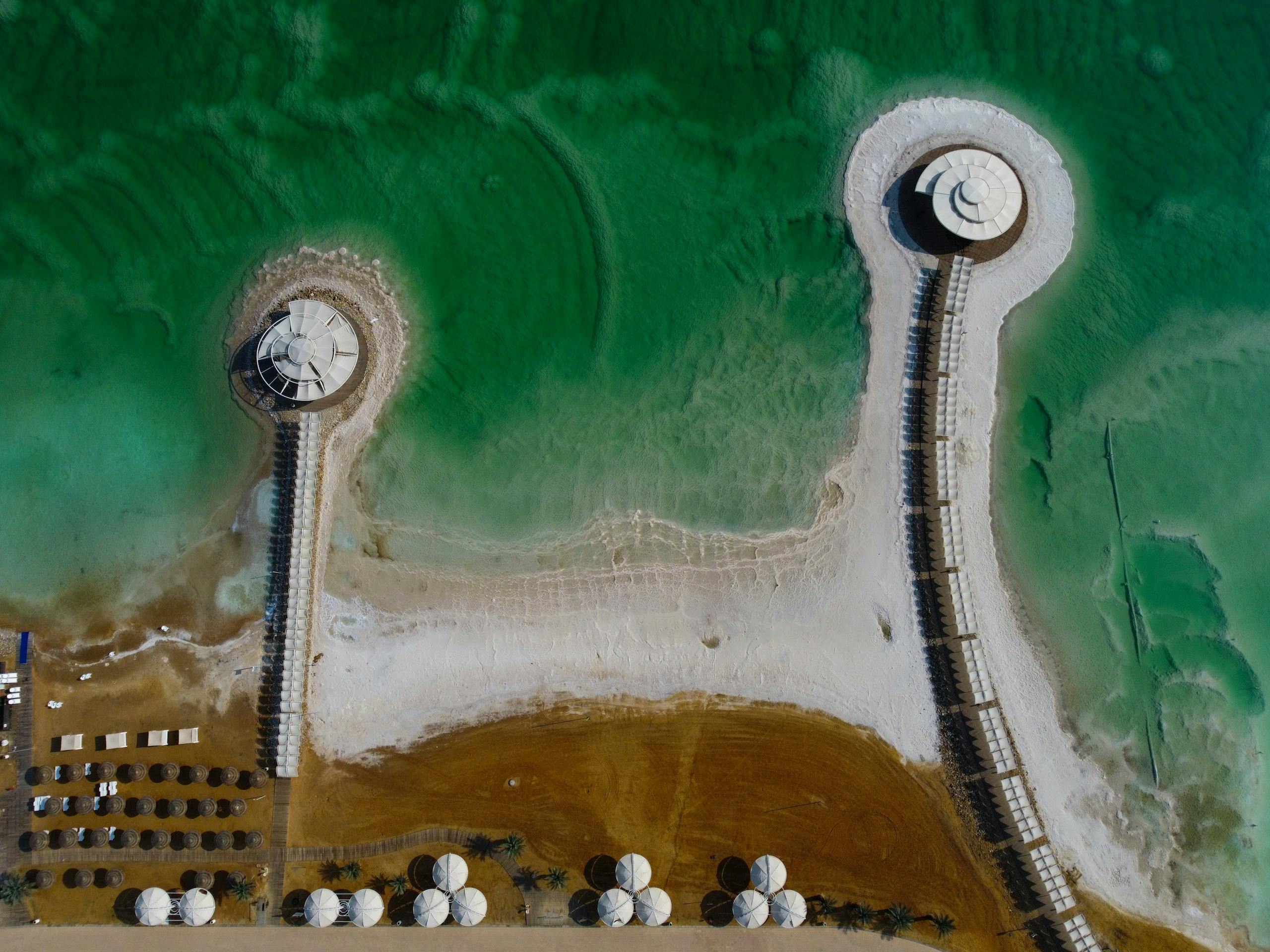 Stunning drone shot of the Dead Sea's salt formations and pavilions, showcasing unique water patterns in Israel.