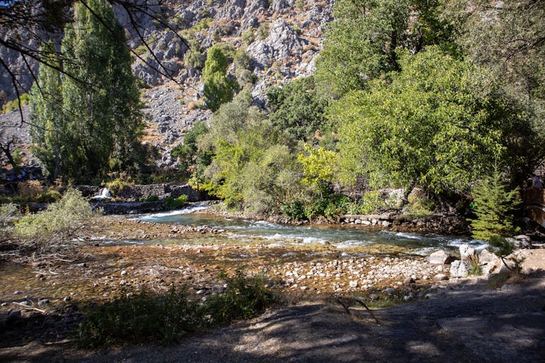 Tranquil river view in Tunceli, Türkiye, surrounded by lush greenery and rocky terrain.