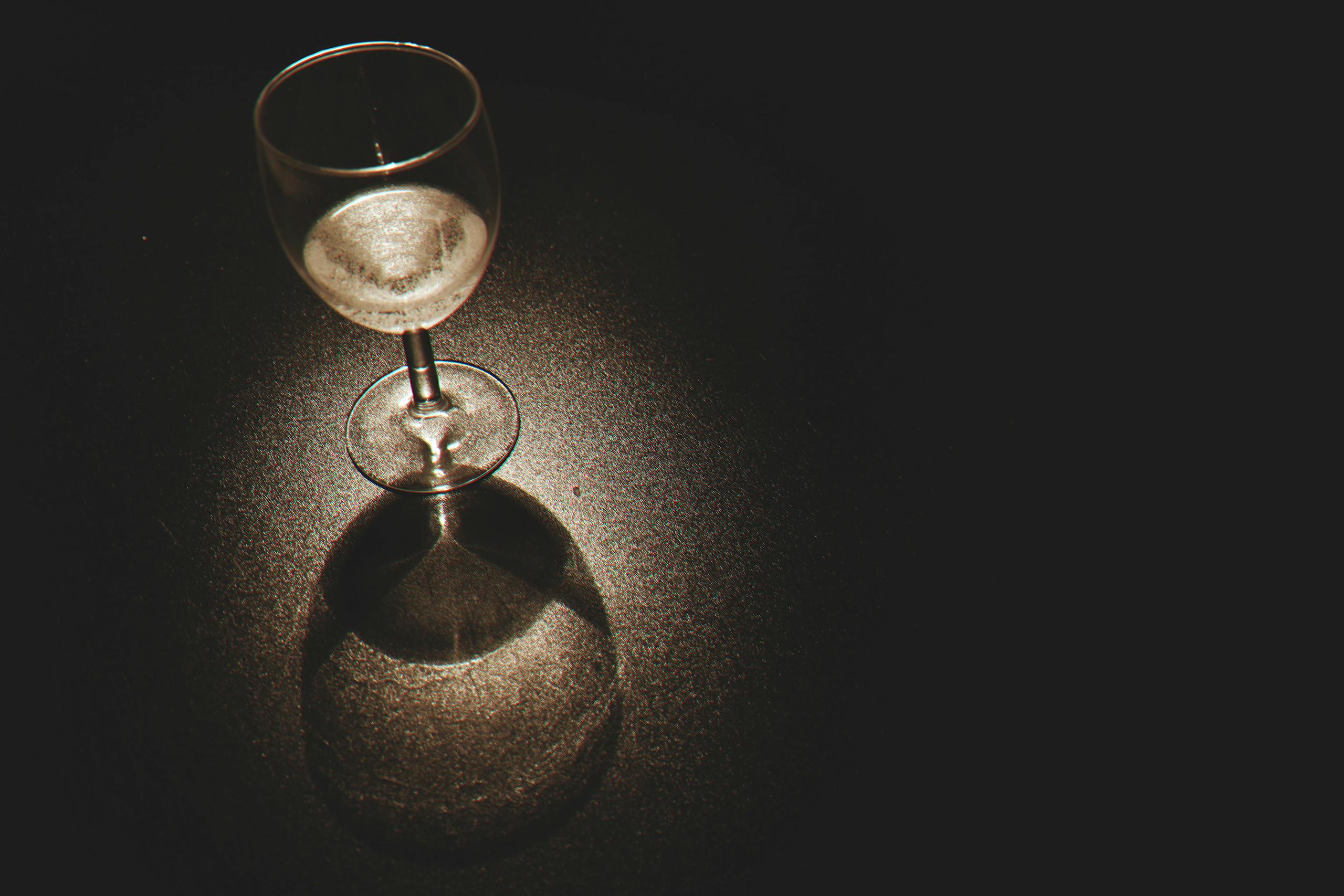 Popular Diabetes and Weight-Loss Drugs Show Promise in Treating Alcohol and Drug Addiction A crystal wine glass casting shadows with light reflections on a dark surface.