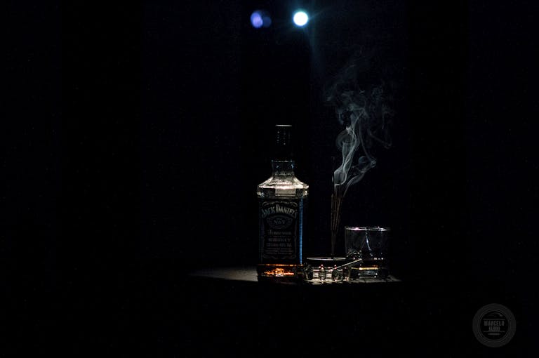 A dramatic whiskey bottle with smoke on a dark background, accented by soft lighting.