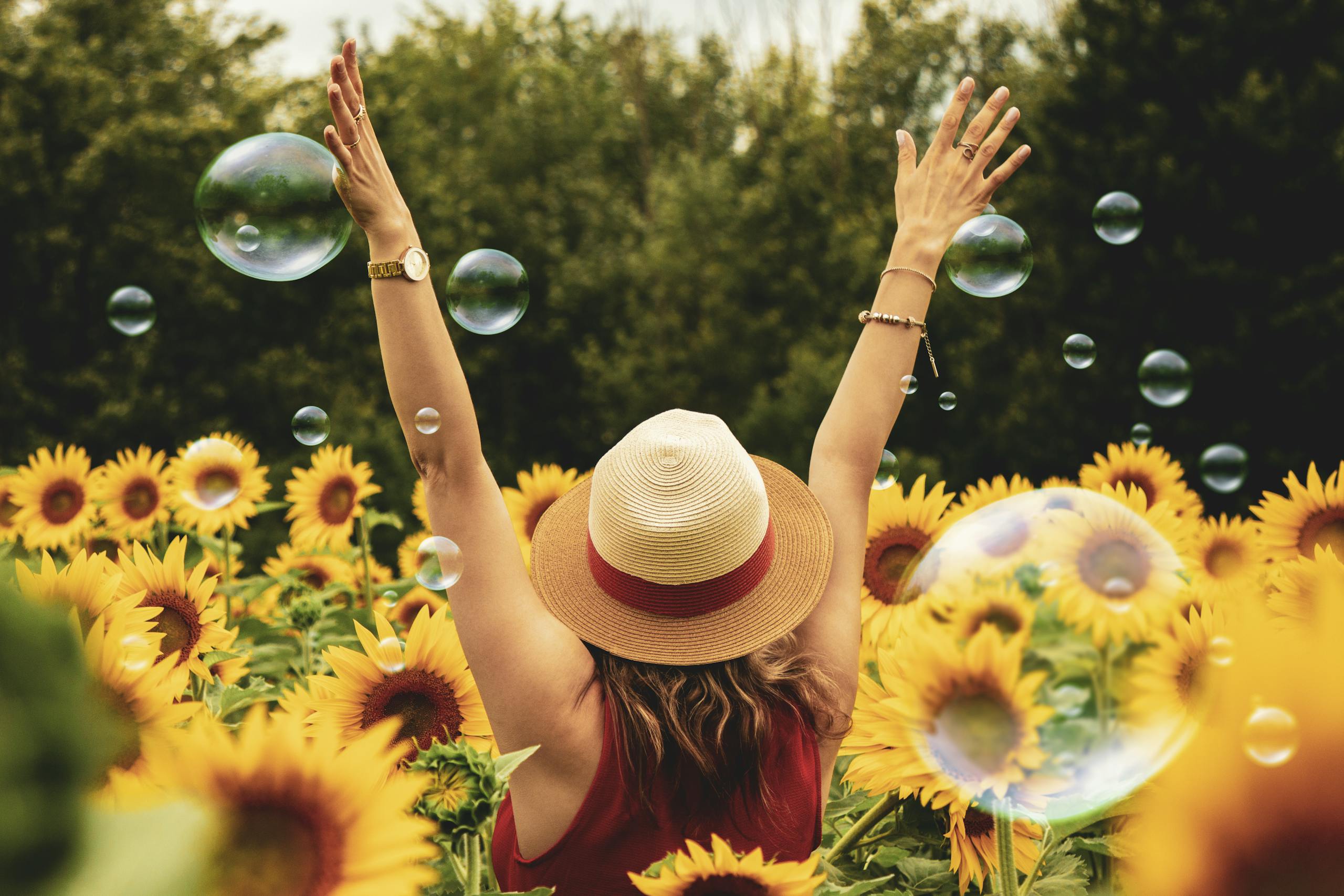 Why Emotional Moments Make Ordinary Memories Stick A joyful woman in a sunflower field with bubbles, expressing happiness on a summer day.