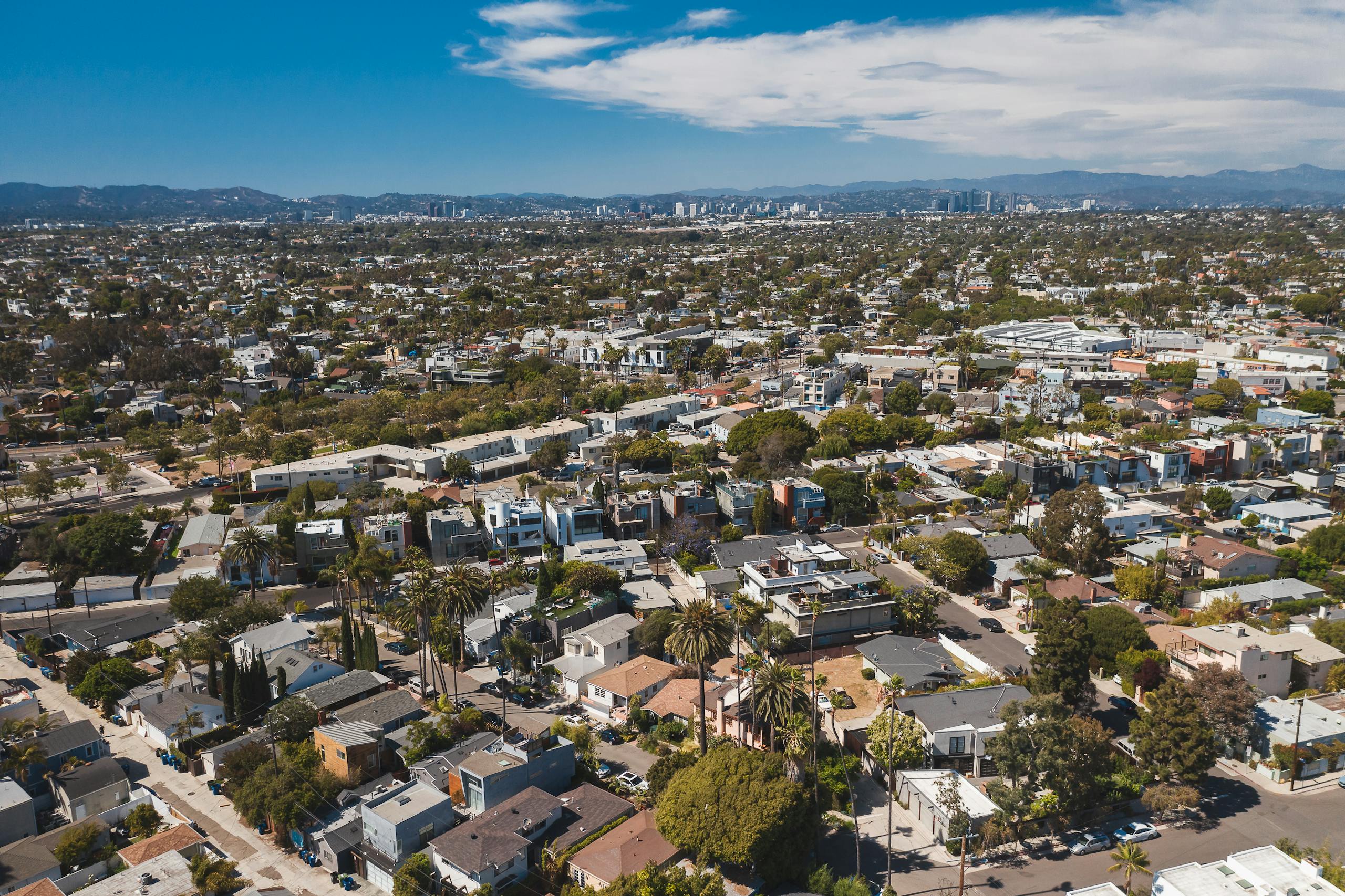 Understanding Anticipatory Action for Health in a Changing Climate Aerial image capturing a sprawling residential area with a distant city skyline under a clear blue sky.