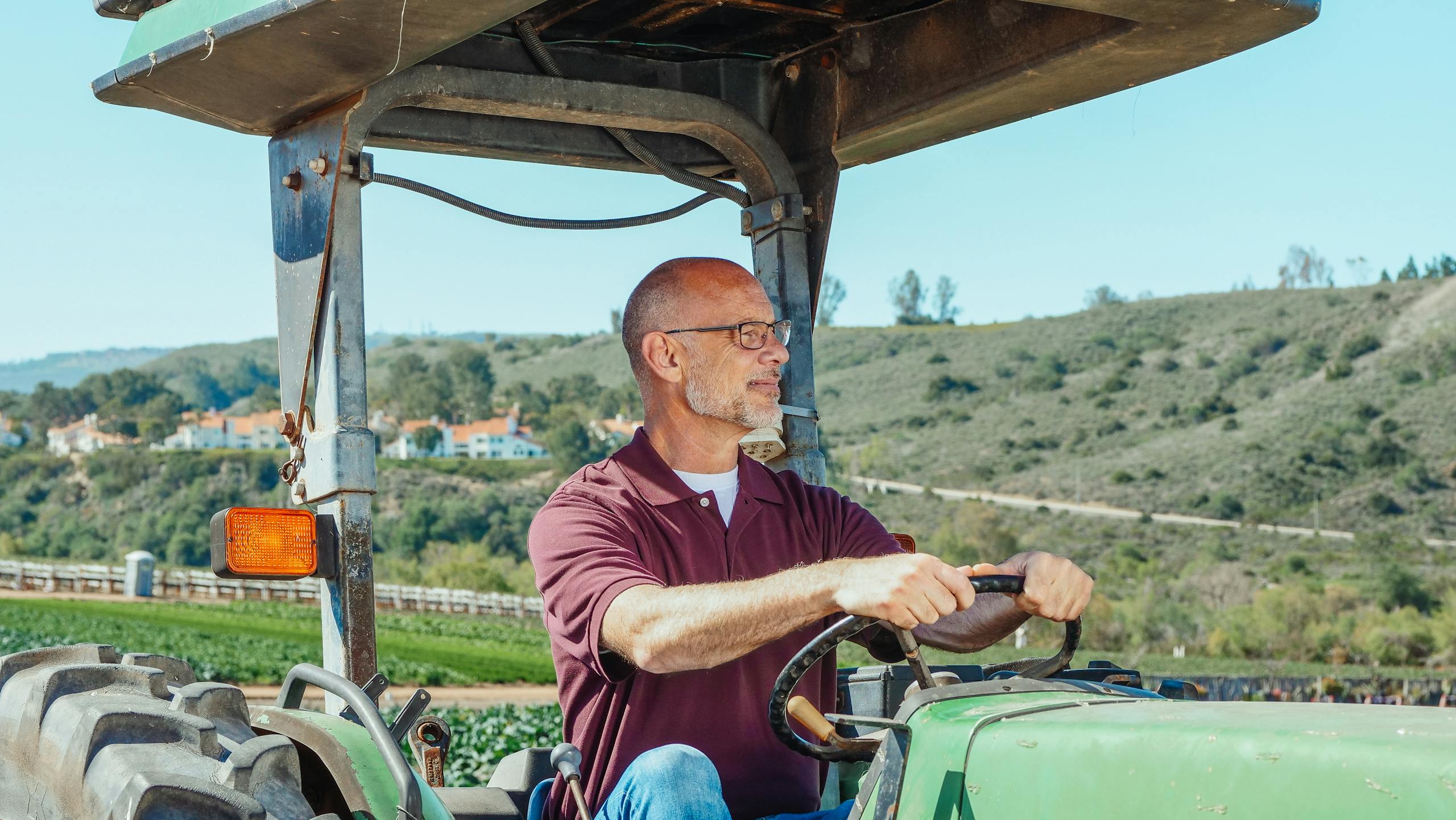 Mapping Rural Heat in California: How Researchers Are Protecting Farmworkers from Extreme Temperatures Experienced farmer operating a tractor in a sunny rural landscape with fields and hills.