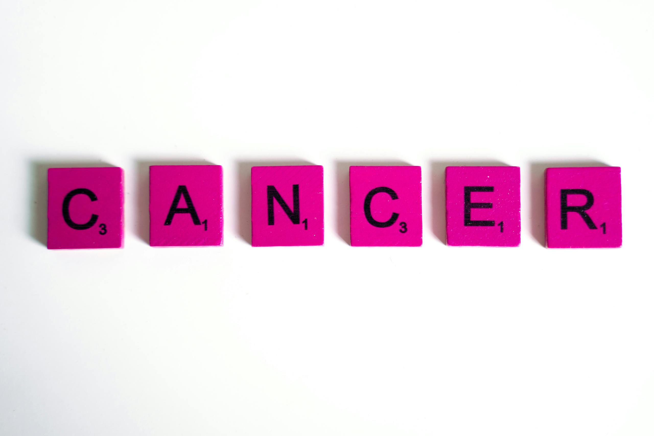 New Cancer Therapy Uses Bacteria to Sneak Viruses Into Tumors and Destroy Them From Within Word 'cancer' spelled with pink letter tiles on a white background symbolizing awareness.