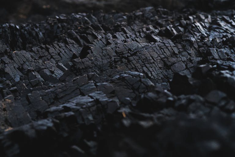 A detailed close-up of dark charcoal texture, showcasing its rough and jagged surface.