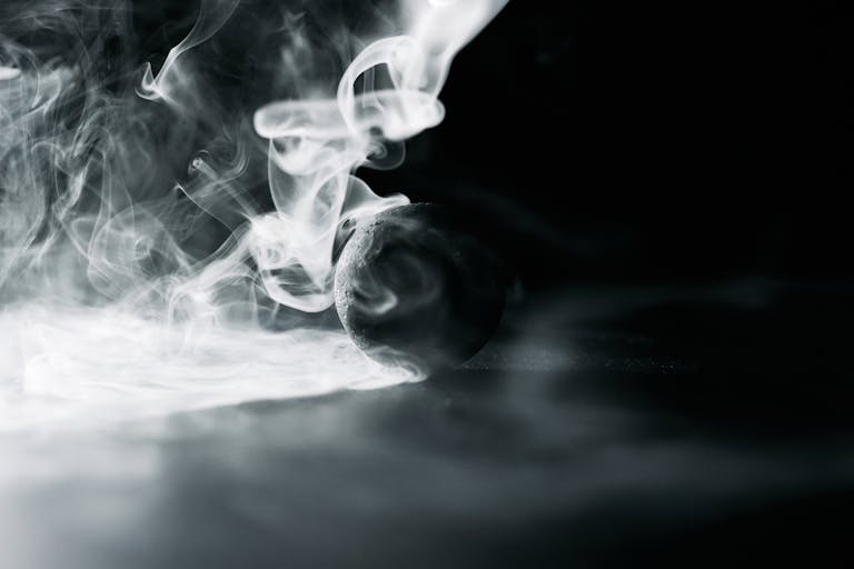 A dramatic black and white image of smoke swirling around a lone sphere, creating a mysterious and artistic effect.