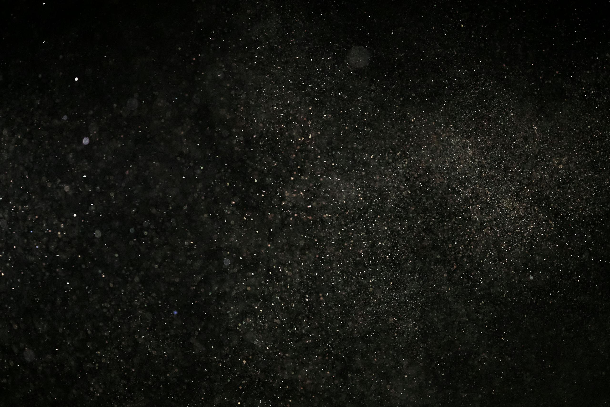 Dark textured background with floating particles, perfect for abstract designs.