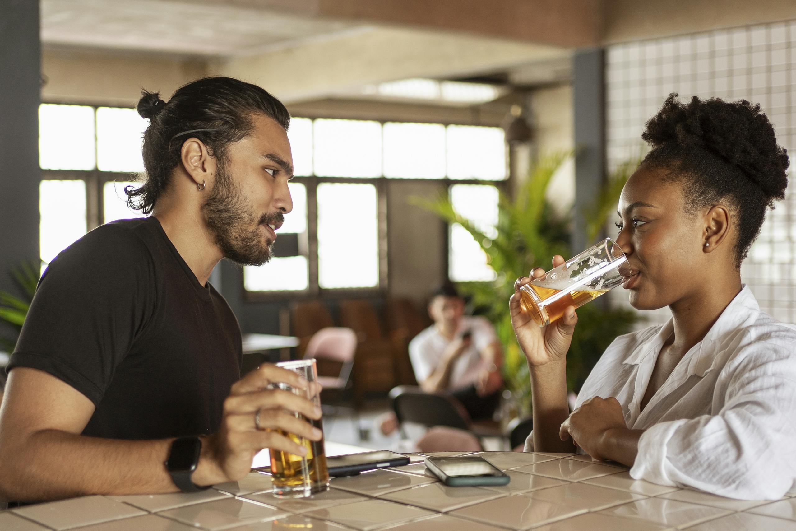 Two adults enjoying drinks and conversation in a relaxed bar setting.
