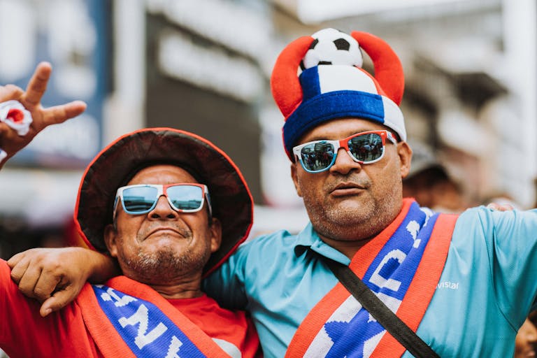 Two joyful soccer fans in vibrant attire show their excitement outdoors.