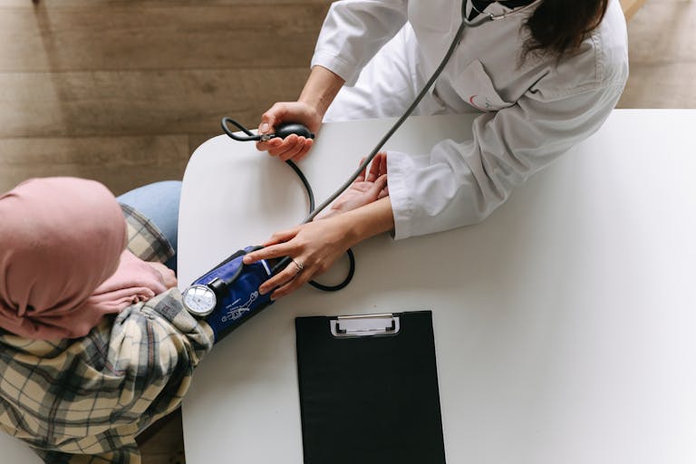 A medical practitioner checks a patient's blood pressure in a clinical setting, showcasing healthcare service.