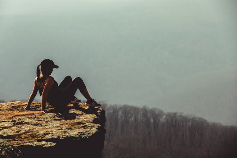 A woman sitting on a cliff edge, enjoying the mountain view in Winslow, Arkansas.
