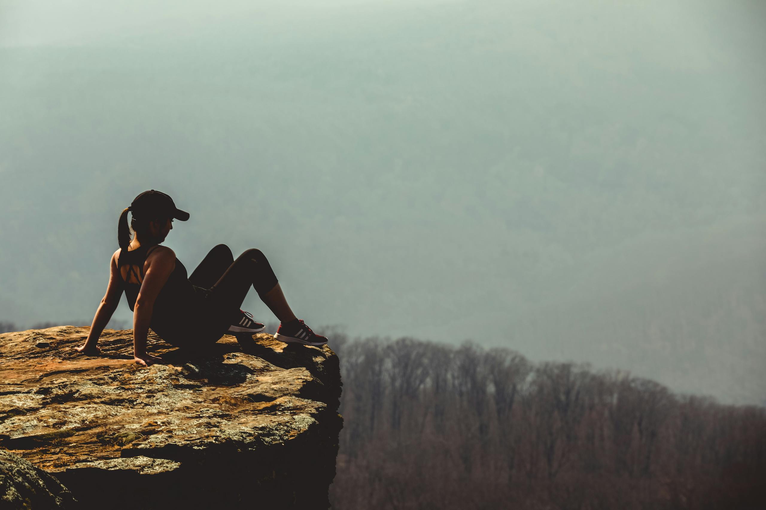 A woman sitting on a cliff edge, enjoying the mountain view in Winslow, Arkansas.