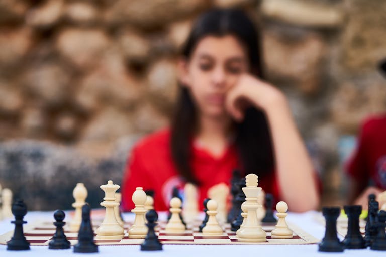 Child deeply focused on a strategic chess game outdoors in Turkey.