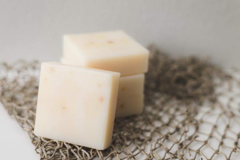 Close-up of creamy cheese blocks stacked on netting, perfect for food photography.