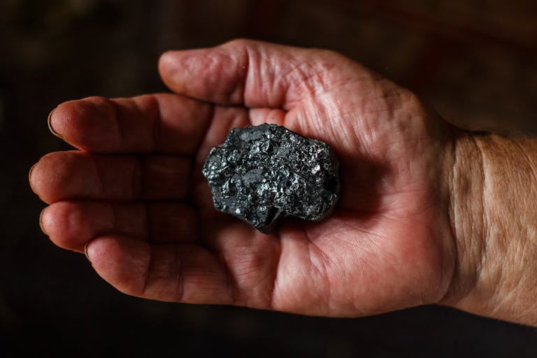 Close-up view of a hand displaying a piece of coal. Ideal for energy or geology themes.