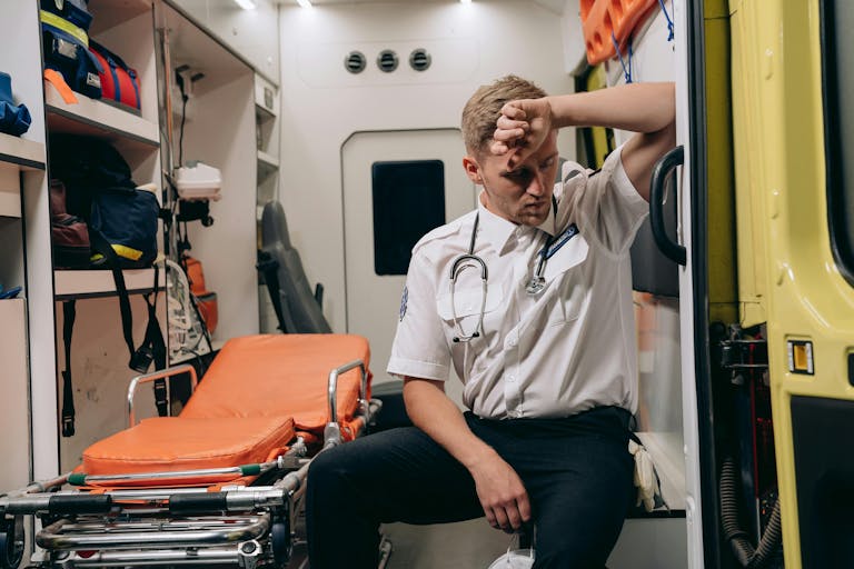 Exhausted paramedic sitting inside an ambulance, reflecting a challenging day.