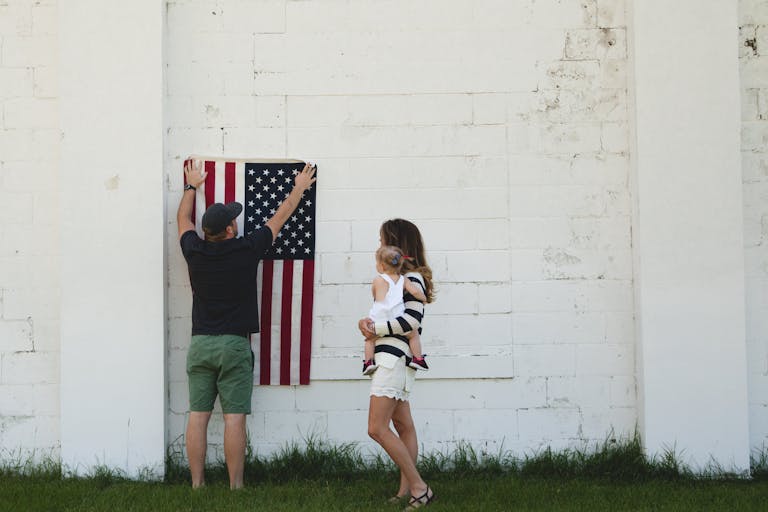 Family celebrating with American flag outdoors, symbolizing patriotism and togetherness.