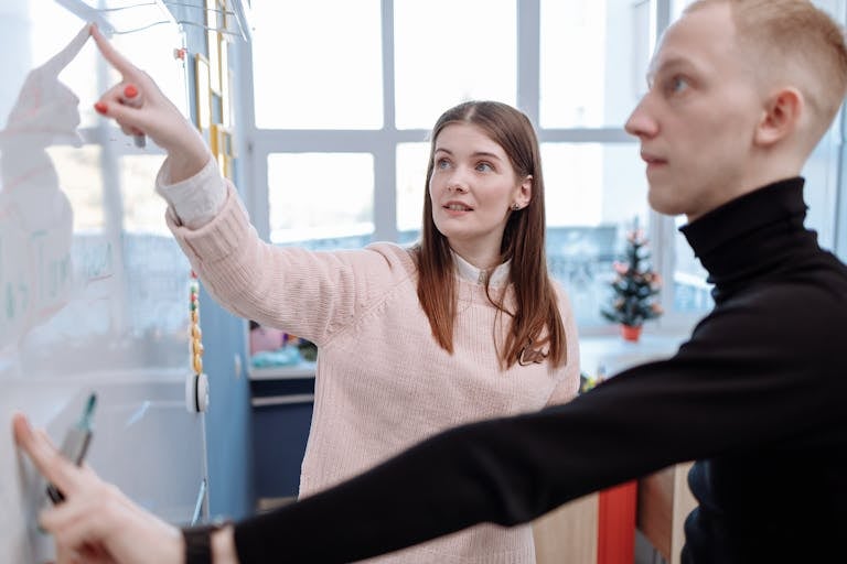 Focused teamwork session with young adults at a whiteboard in modern office setting.