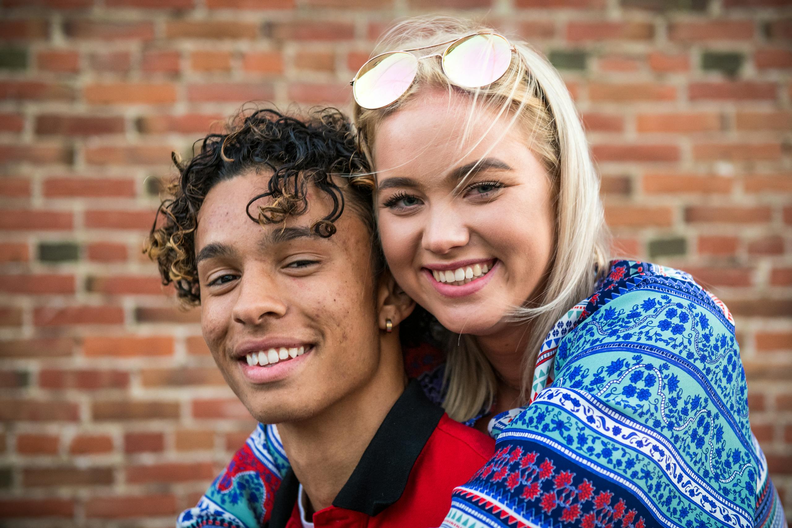 Joyful young couple embracing against a brick wall in San Luis Obispo.
