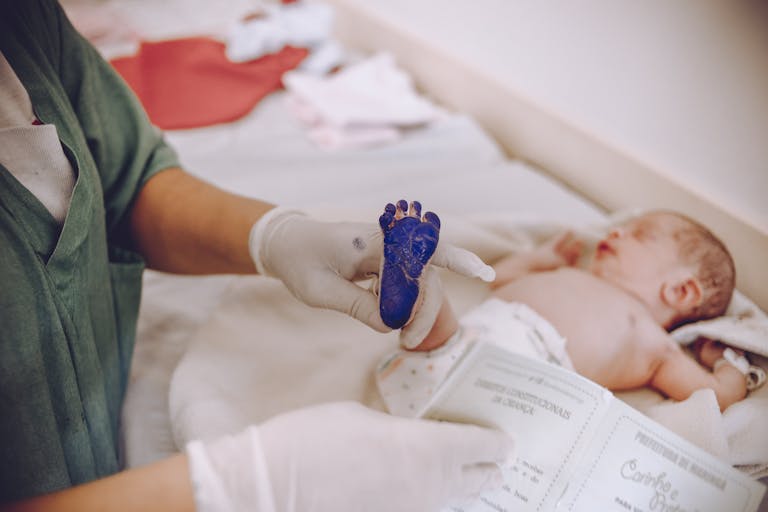 Medical professional taking footprint of a newborn baby in hospital setting.