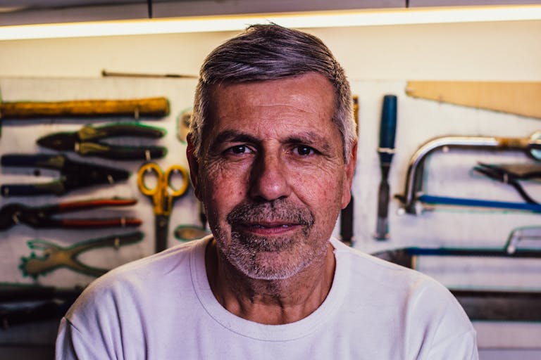 Portrait of a senior man with tools in the background, exuding confidence.