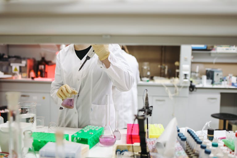 Scientist in a lab coat handling samples for scientific research in a modern laboratory setting.