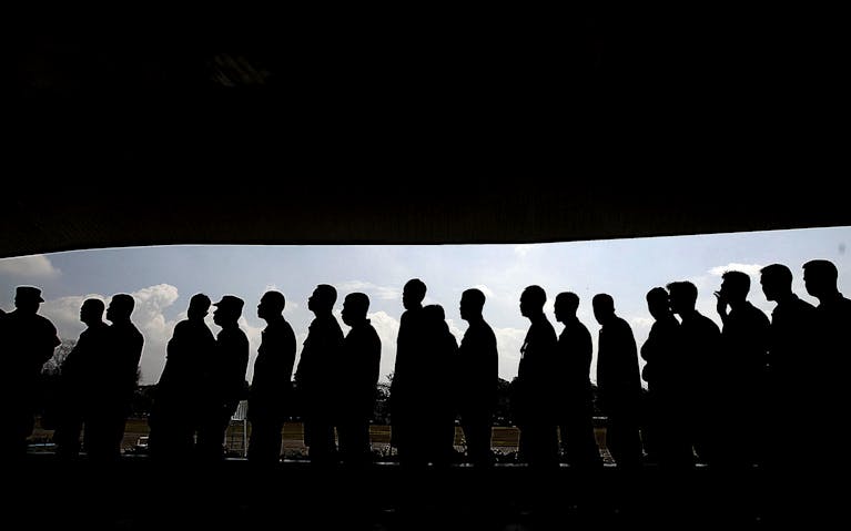 Silhouettes of people in line under a shaded canopy, highlighting social interaction and society.