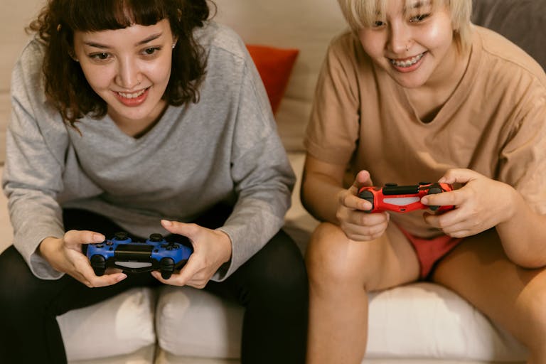 Two women playing video games with controllers, enjoying leisure time indoors.