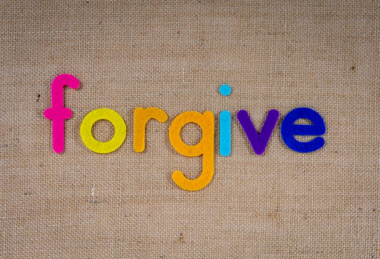 Vibrant felt letters spelling 'forgive' on a burlap background.