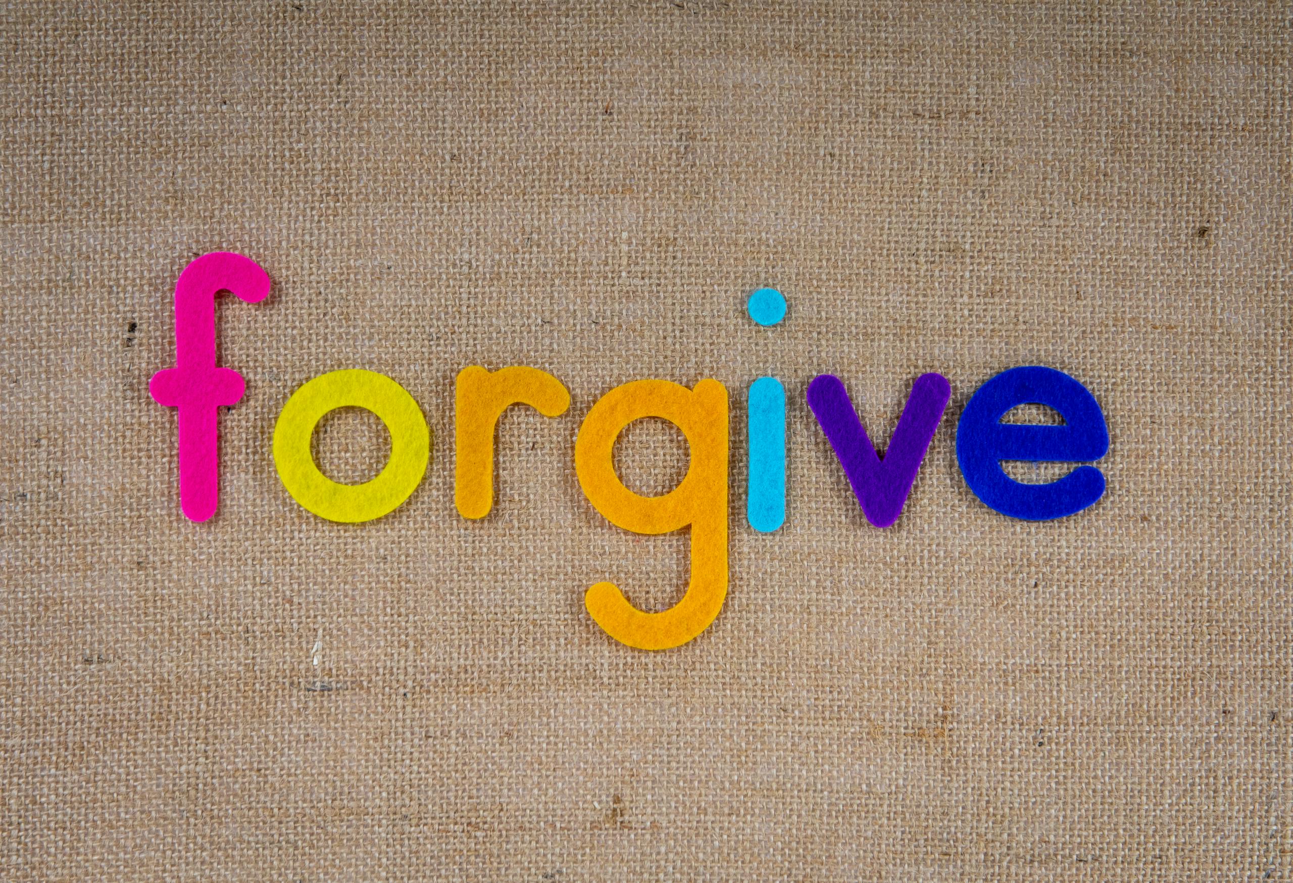 Vibrant felt letters spelling 'forgive' on a burlap background.