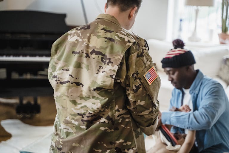 A soldier in camouflage uniform interacts with family at home, evoking themes of service and togetherness.