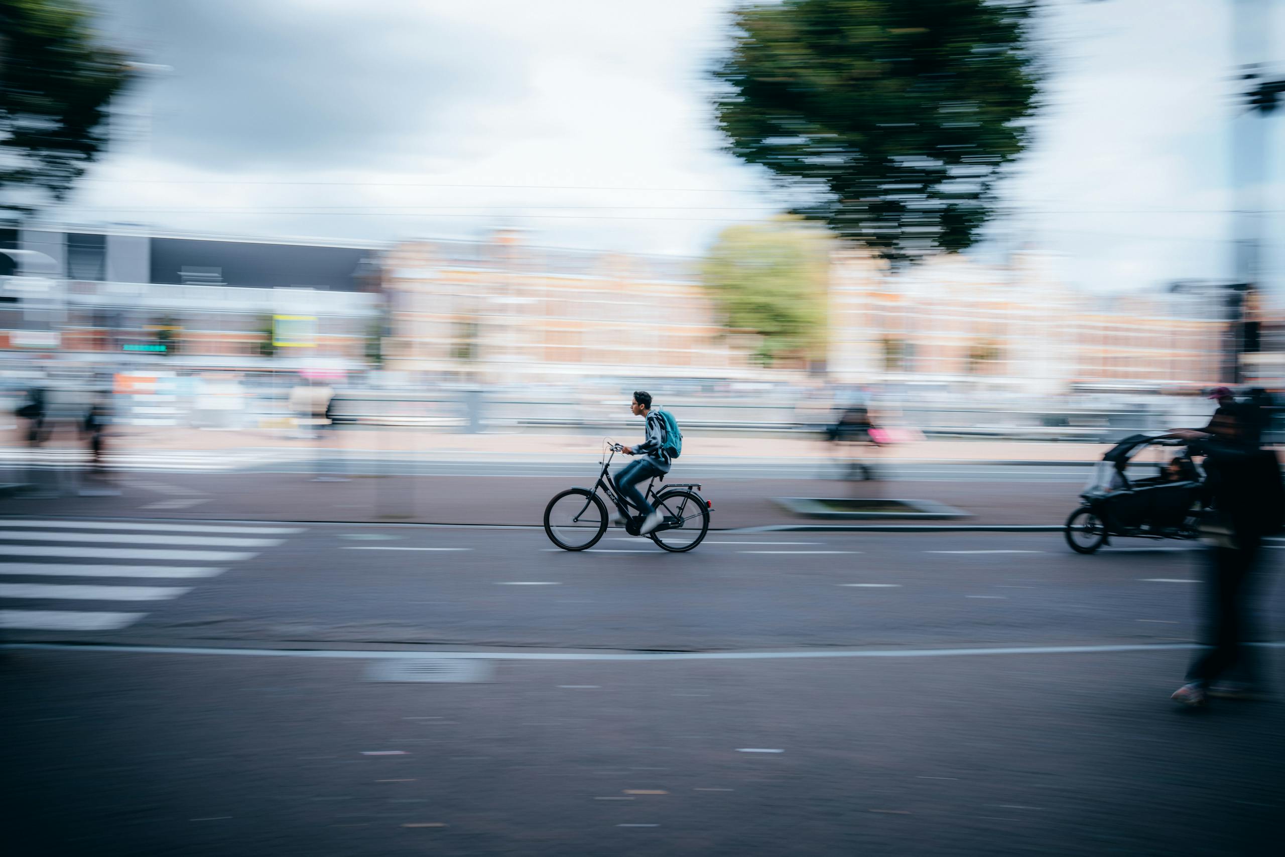 Blurred motion of a cyclist riding through a city street, capturing urban hustle.