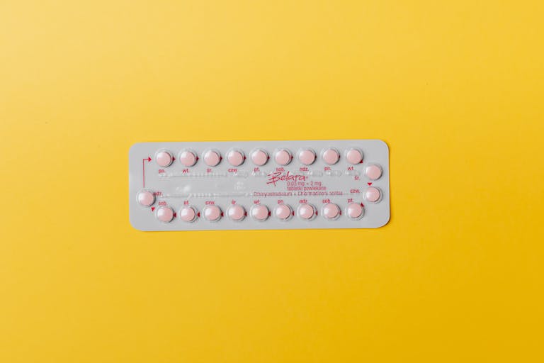 Close-up of a blister pack of pink pills on a vivid yellow background for medication concept.