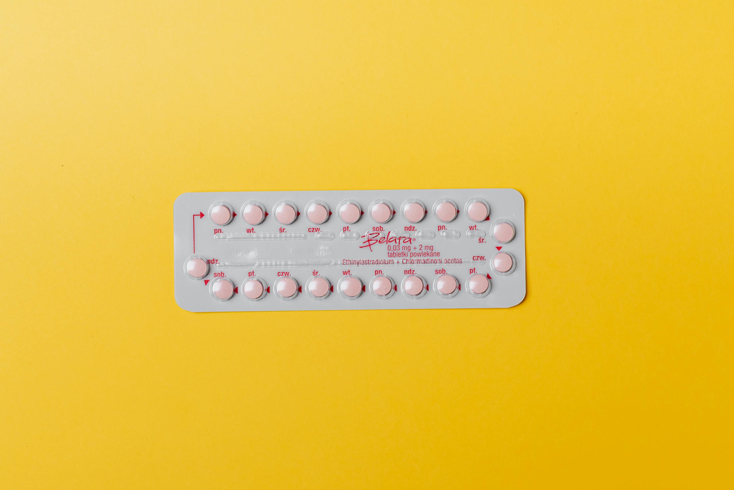 Close-up of a blister pack of pink pills on a vivid yellow background for medication concept.